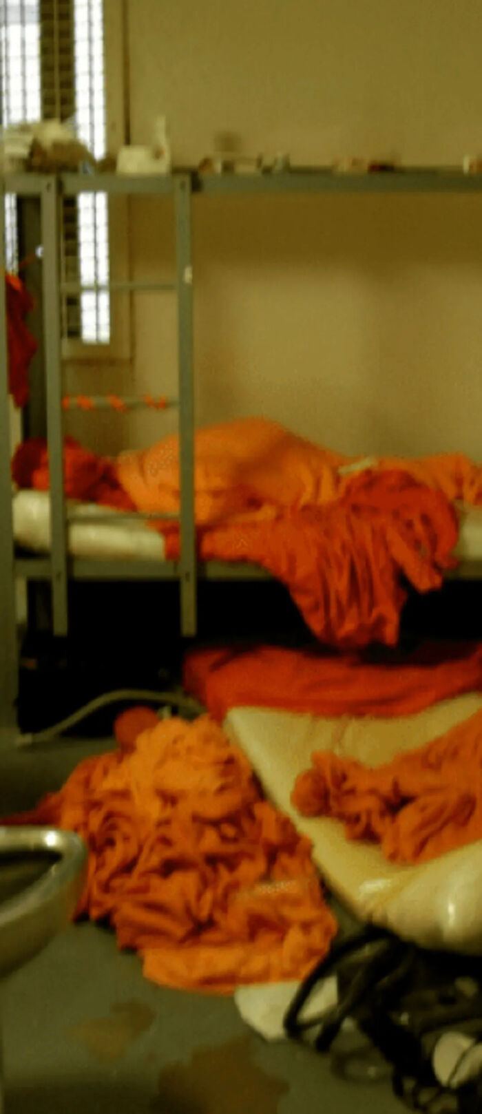 Prison cell interior with orange blankets and bunk beds, related to efforts to resuscitate Jeffrey Epstein.