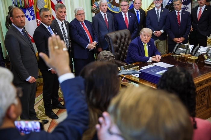Donald Trump seated at White House desk with group of officials during meeting