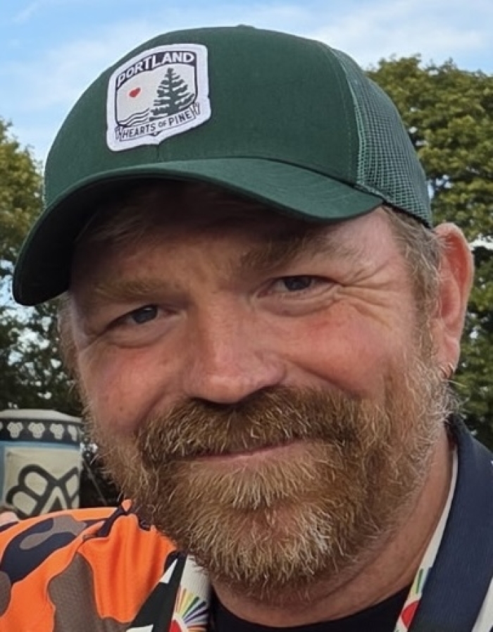 Close-up of Graham Platner wearing Portland Hearts of Pine cap outdoors