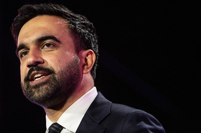 A man with a beard and dark suit, possibly a supporter or part of the democratic socialist campaign.
