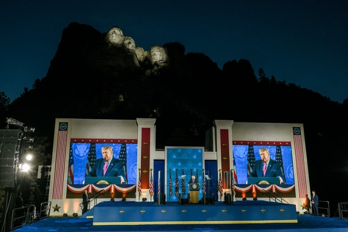 President Trump speaking at a podium under Mount Rushmore, with screens displaying him, regarding the House GOP's defense plan. President Trump speaking at a podium under Mount Rushmore, with screens displaying him, regarding the House GOP's defense plan.