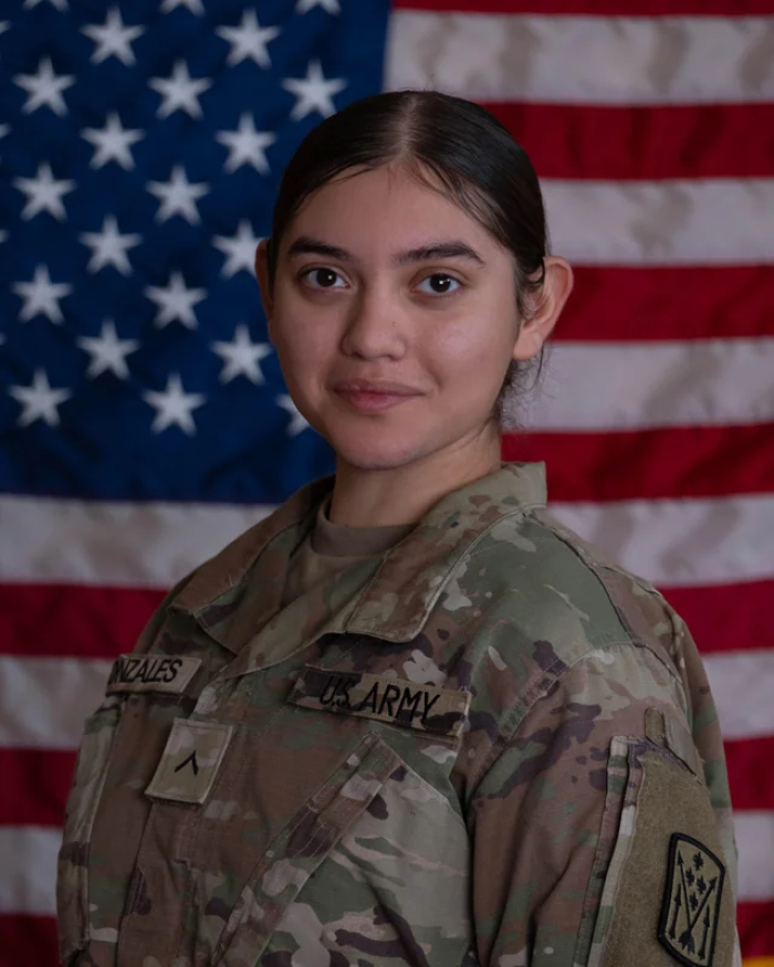 Female U.S. service member in uniform in front of an American flag, after Iranian strike on Jordan base.