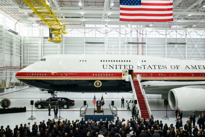 Air Force One on display in a hangar with a crowd, highlighting defense systems comparison to Qatari Jet. Air Force One on display in a hangar with a crowd, highlighting defense systems comparison to Qatari Jet.