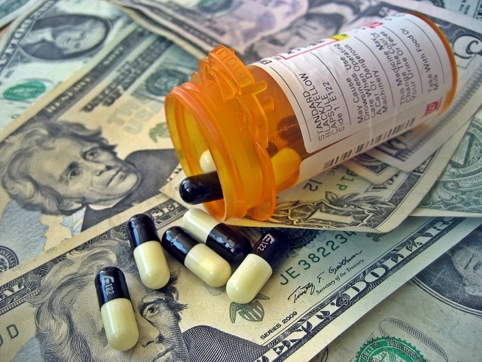 Prescription pills spilling onto US dollar bills, representing Medicaid funds.