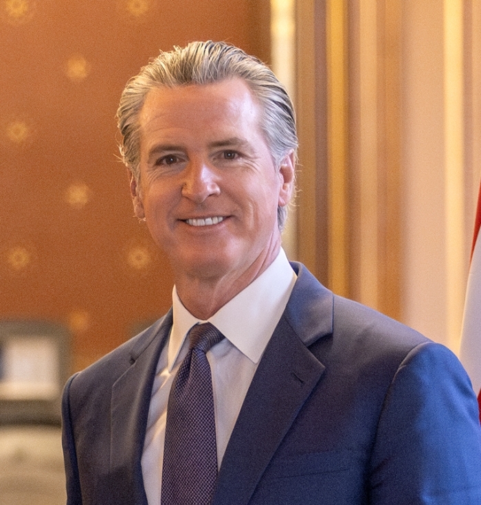 California Governor Gavin Newsom smiling in a suit, related to Medicaid funds.